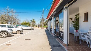 A parking lot with several cars, a building with a red roof, and outdoor seating with chairs. - Modern studio apartment - La Higuera 3 (Cadiz)