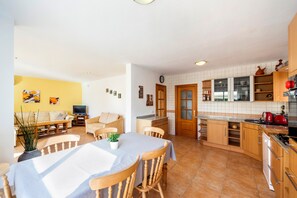 Una sala de estar con sofá, televisor y una mesa de comedor con sillas.