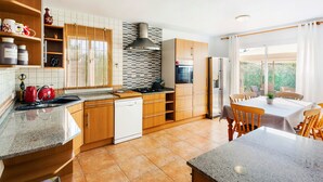 Eine moderne Küche mit Holzausstattung, einem Einbauofen und einem Essbereich mit Tisch und Stühlen.