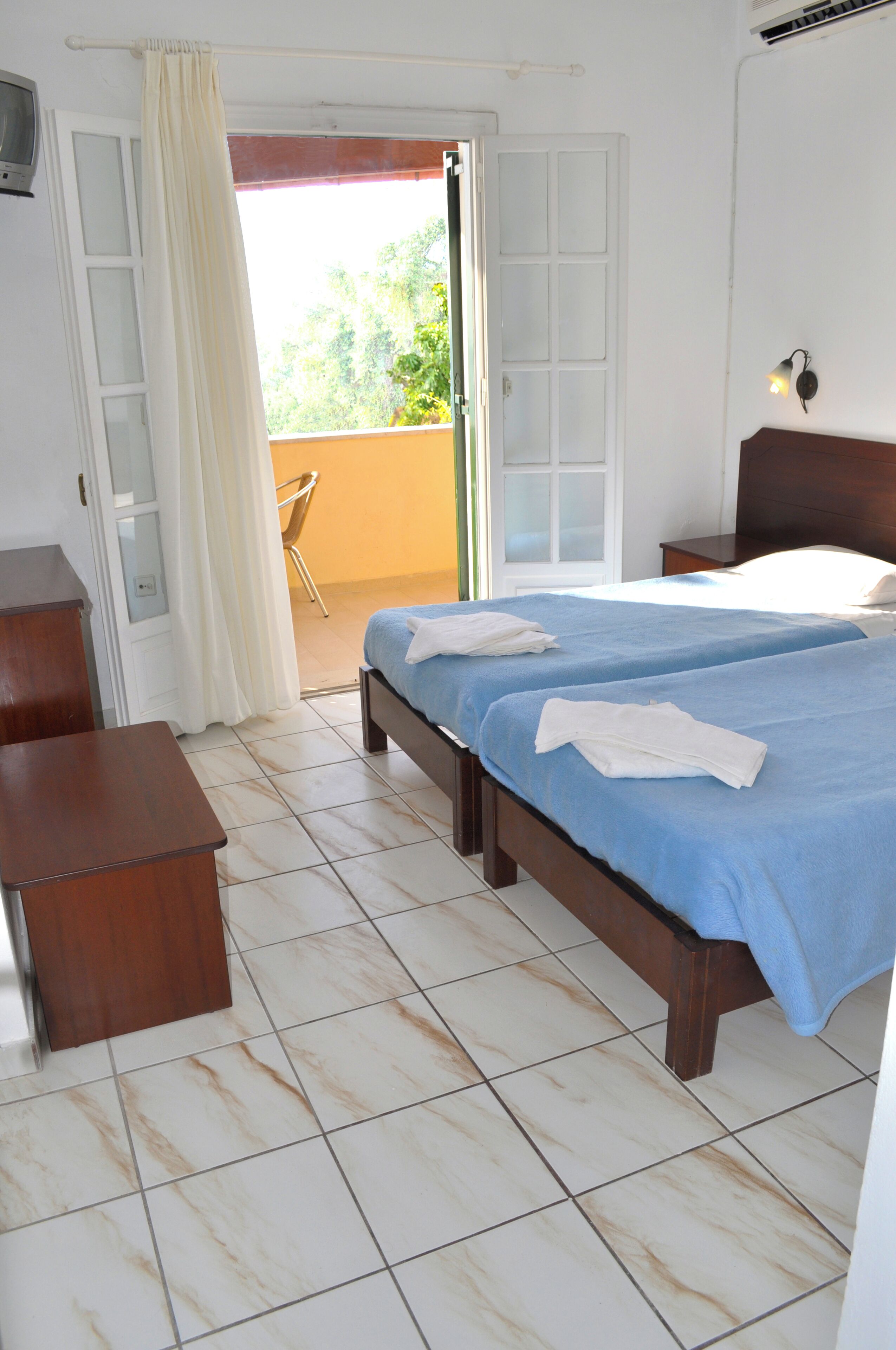 A room with two beds, a wooden desk, and a chair.