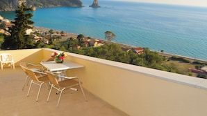 A balcony with wicker chairs, a table, and a vase of flowers. - Holiday House With Pool Maria on Agios Gordios Beach (Corfu)