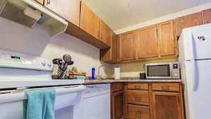 A kitchen with wooden cabinets, a white stove, a microwave, and a dishwasher.