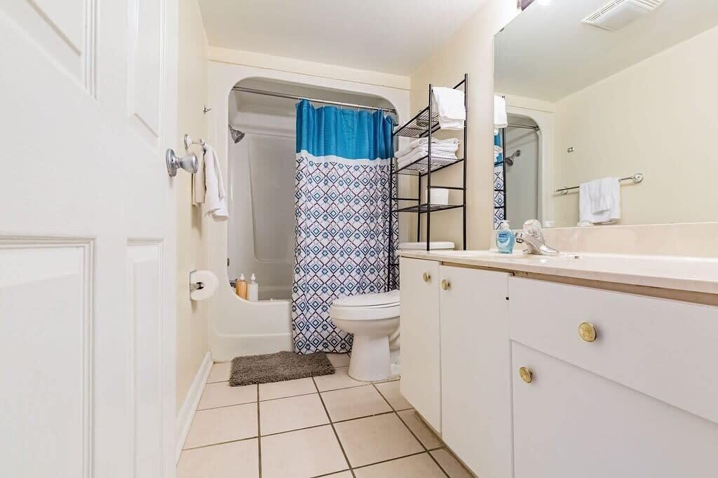 A bathroom with a bathtub, toilet, and a shower curtain.