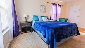 A bedroom with a bed, nightstand, lamp, and curtains.