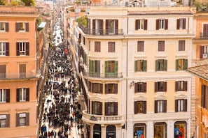 A crowded street with buildings featuring storefronts, including a visible 'Dior' sign. - 19 Steps Trevi (Rome)