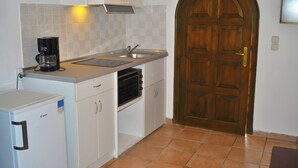 Una cocina compacta con horno integrado, cafetera y lavamanos.