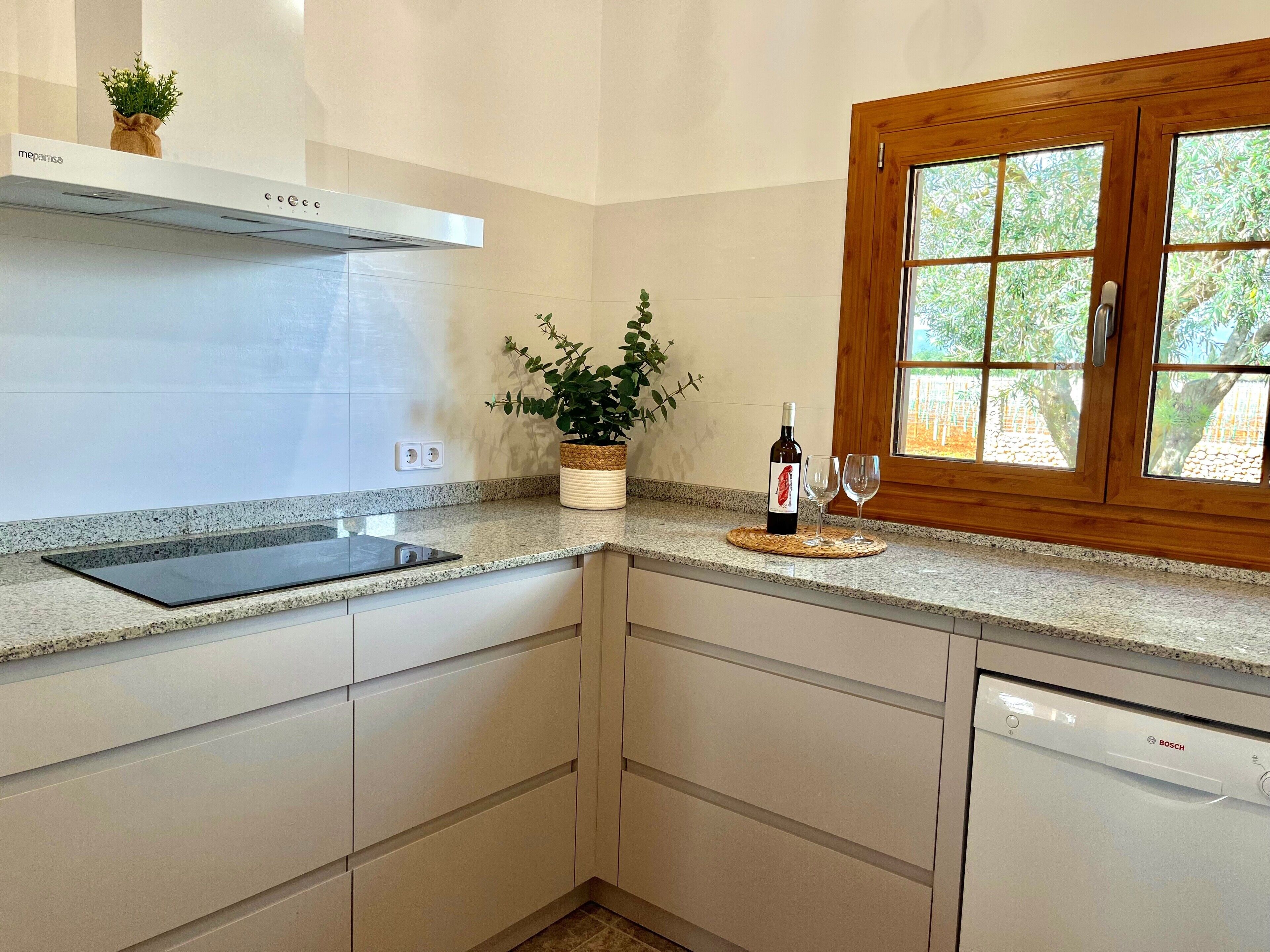 A kitchen with a Bosch dishwasher, a wine bottle, and glasses on the counter.