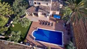 Una casa espaiosa amb piscina, envoltada d'arbres i una palmera.