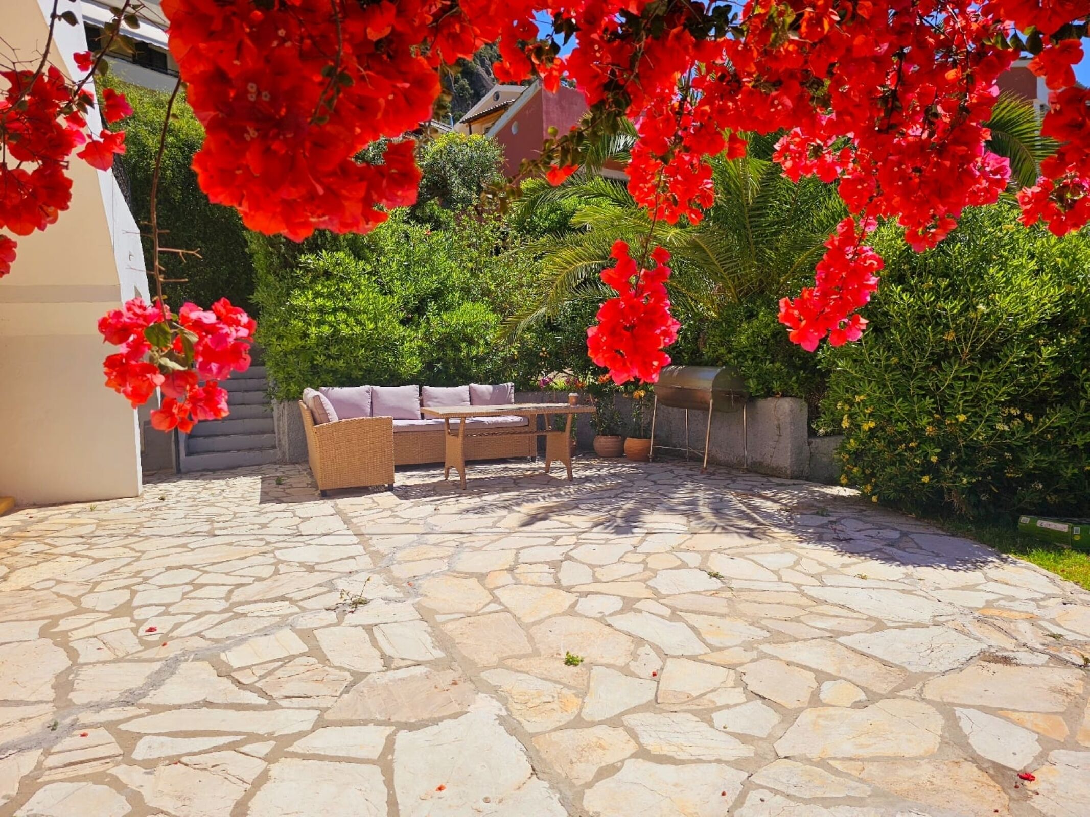 A patio area with stone flooring, a wicker sofa, and a table.