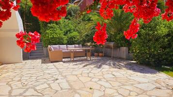 A patio area with stone flooring, a wicker sofa, and a table.