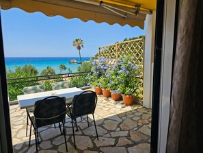 A terrace with a table and chairs, a wooden fence, and a view of the sea. - Corfu Glyfada Menigos Resort 45 (Corfu)