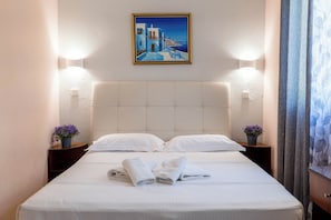 A hotel room with a bed, pillows, a painting, bedside tables with flowers, and a curtain. - Corfu Glyfada Menigos Resort 45 (Corfu)
