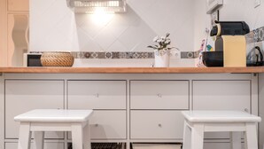 Une cuisine avec des armoires blanches, un plan de travail en bois et un tabouret blanc.