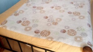 Un lit avec une couvre-lit à motifs, une tête de lit en bois et un cadre en métal.