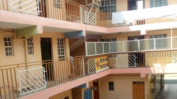 Un immeuble à plusieurs étages doté de balcons, d’un espace d’accueil et d’une enseigne indiquant une offre « meilleur rapport qualité-prix ».