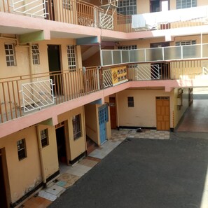 Un immeuble à plusieurs étages doté de balcons, d’un espace d’accueil et d’une enseigne indiquant une offre « meilleur rapport qualité-prix ».