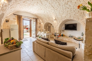 Un intérieur aux murs de pierre, comprenant un canapé, un coin repas et une cuisine.