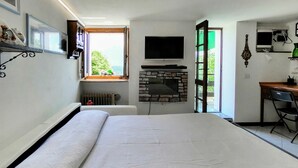 A bedroom with a bed, a fireplace, a TV, and a desk. - Cosy apartment for 3 guests with WIFI, TV, patio and pets allowed (Peglio)