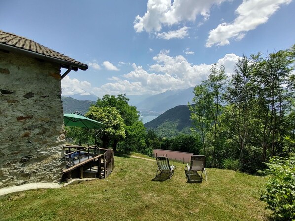 Un edificio de piedra con una terraza, dos sillas y una sombrilla verde.
