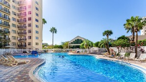 A swimming pool with lounge chairs and palm trees.