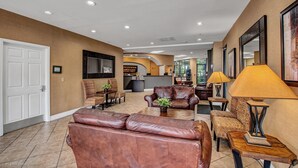 A spacious lobby with leather sofas, a coffee table, and a TV mounted on the wall.