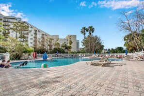 A swimming pool area with lounge chairs and a Coca-Cola cooler.