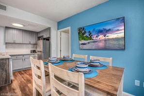Enjoy meals in the kitchen with a dining area for four, featuring a wooden table and a beautiful beach scene above.