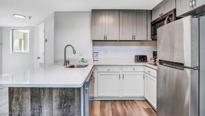 A modern kitchen with white cabinets, stainless steel appliances, and a large island with a sink.