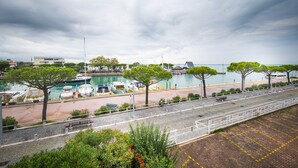 A waterfront promenade with a paved walkway, benches, and trees. - Yachting Residence (Lignano Sabbiadoro)