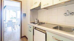 A kitchen with white cabinets, a stainless steel sink, and a built-in oven. - Yachting Residence (Lignano Sabbiadoro)