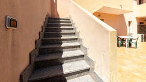 Un escalier menant à un balcon aménagé avec du mobilier d’extérieur.