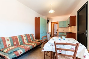 Un espacio habitable compacto con sofá, mesa de comedor, sillas y kitchenette.
