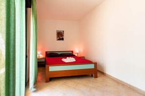 Un dormitorio con una cama, dos lámparas de noche, una mesita de noche, un cuadro en la pared y una cortina verde.