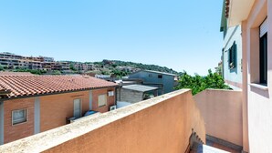 Un quartier résidentiel avec des bâtiments aux toits de tuiles en terre cuite, un balcon et une colline en arrière-plan.