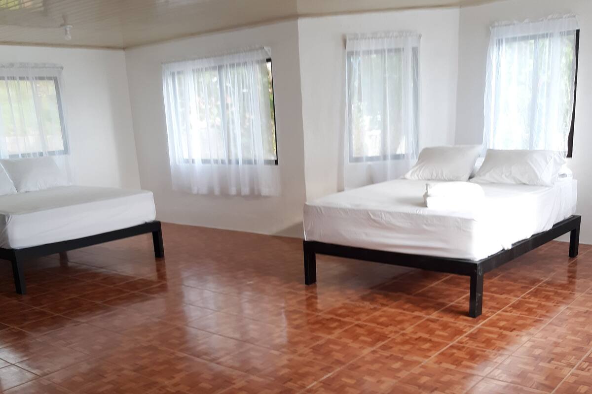 A spacious room with a large bed, a smaller bed, and a bench.