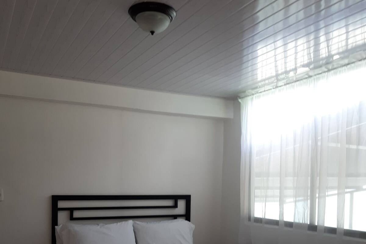A single bed with a black frame in a room with white walls and a sloped ceiling.