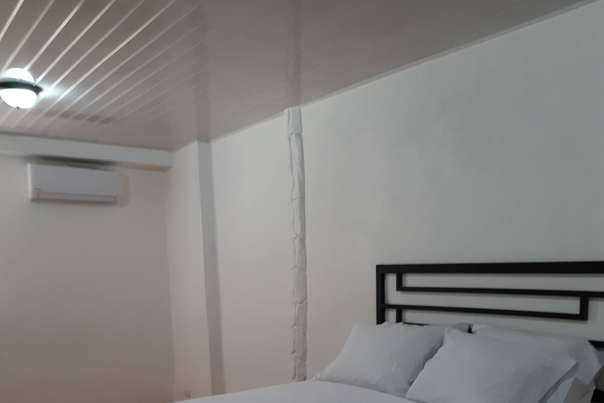 A single bed with white bedding in a room with white walls and a wooden floor.