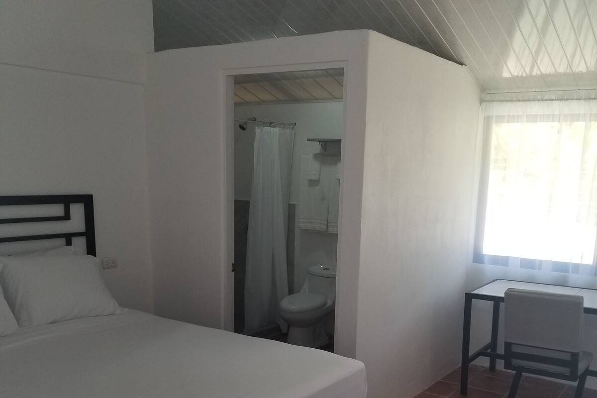 A bedroom with a bed, a desk, and a chair.