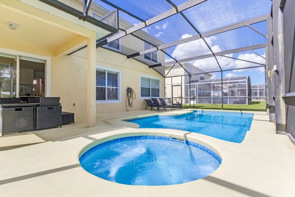 A pool area with two pools, a covered patio, and outdoor furniture.