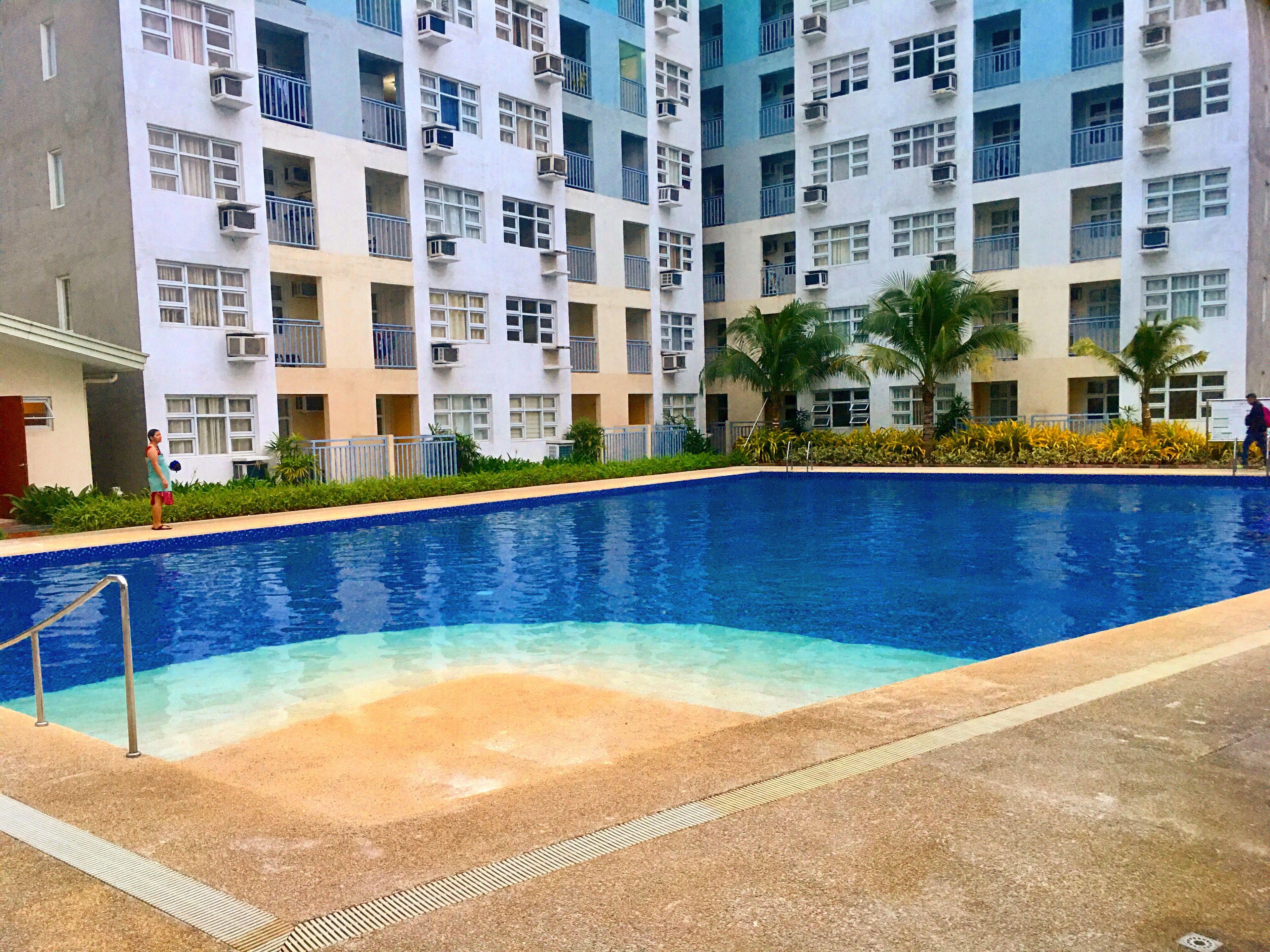 A swimming pool with a clear blue water, surrounded by a concrete deck.
