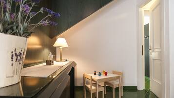 Een gezellig eethoekje met een tafel, stoelen, een lamp en een bloemetjesvaas.