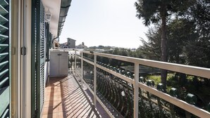 A balcony with a metal railing, a tiled floor, and a view of a garden and buildings in the distance. - Casa Vacanza Argo (Sperlonga)