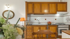 A kitchen with wooden cabinets, a stove, and a sink. - Casa Vacanza Argo (Sperlonga)