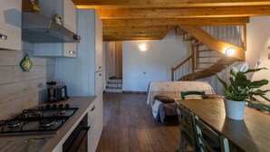 Eine Küche mit Gaskochfeld, Holzbalkendecke und einem Essbereich mit Tisch und Stühlen.