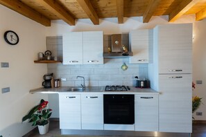 A modern kitchen with white cabinets, a stainless steel sink, a gas stove, and a built-in oven.