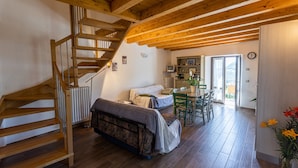 Eine Holztreppe, ein Bett, ein Essbereich und eine Küche in einem rustikalen Interieur.