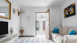 A living room with a sofa, a television, a decorative mirror, and a door leading to another room.