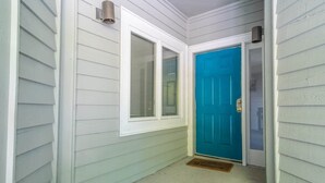 A narrow hallway with white siding, a blue door, and a window with blinds. - Tidewater- Teal lake #2521 (North Myrtle Beach)