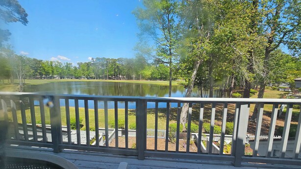 A wooden deck with a view of a lake and trees. - Tidewater- Teal lake #2521 (North Myrtle Beach)