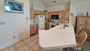 A kitchen with wooden cabinets, a refrigerator, a microwave, a stove, and a sink. - Tidewater- Teal lake #2521 (North Myrtle Beach)